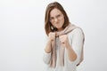 Studio shot of rebellious daring and playful female friend in glasses and sweatshirt tied over neck raising clenching