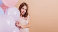 Studio shot of relaxed european girl celebrating her birthday. Indoor portrait of stunning young lady isolated on light