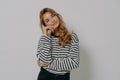 Studio shot of satisfied young European woman keeps hand on face tilts head looks gently at camera Royalty Free Stock Photo