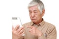 Senior Japanese man using tablet computer looking confused Royalty Free Stock Photo