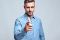 Who are you Serious handsome man in blue shirt pointing his finger at you and looking at camera while standing against Royalty Free Stock Photo