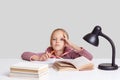 Studio shot of serious intelligent small schoolgirl keeps hand on head, looks with tired expression directly at camera, learns new Royalty Free Stock Photo