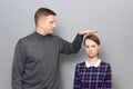 Tall man is showing height of short woman, people of different heights Royalty Free Stock Photo