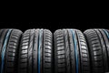 Studio shot of a set of summer car tires on black background. Tire stack background. Car tyre protector close up. Black rubber tir Royalty Free Stock Photo