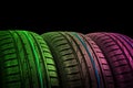 Studio shot of a set of summer car tires in green and pink tones. Tire stack background. Car tyre protector close up. Black rubber Royalty Free Stock Photo