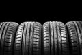 Studio shot of a set of summer car tires isolated on black background. Tire stack background. Car tyre protector close up. Black r