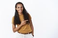 Studio shot of shy and cute pretty young african american woman with long curly hair bending as pointing right with Royalty Free Stock Photo