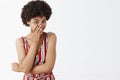 Studio shot of smart and flirty attractive feminine african american in striped overalls chuckling sensual covering