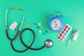 Studio shot of stetoscope, clock, syringe and pills on light green background. Top views Royalty Free Stock Photo