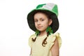 Stylish little Irish baby girl wearing clover leaves earrings and green hat, smiles looking at camera, white background