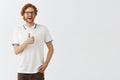 Studio shot of supportive entertained and amused happy redhead bearded guy in casual polo shirt and black glasses