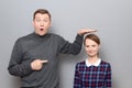 Tall man is showing height of short woman and pointing at her Royalty Free Stock Photo