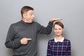 Tall man is showing height of short woman and pointing at her Royalty Free Stock Photo