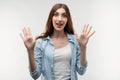 Studio shot of surprised Young female with long chestnut hair smiling happily and raises her hands. Surprise Royalty Free Stock Photo