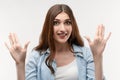 Studio shot of surprised Young female with long chestnut hair smiling happily and raises her hands. Surprise Royalty Free Stock Photo