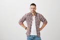 Studio shot of suspicious attractive husband in trendy glasses and stylish outfit, squinting and frowning while standing