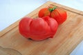 Two coeur du boeuf tomatoes isolated on a wooden cutting board Royalty Free Stock Photo