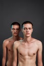 Studio shot of two young caucasian half naked twin brothers looking at camera while posing in studio, standing isolated Royalty Free Stock Photo
