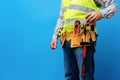 Studio shot of unknown handyman with hands on waist and tool belt with construction tools Royalty Free Stock Photo