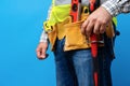 Studio shot of unknown handyman with hands on waist and tool belt with construction tools Royalty Free Stock Photo