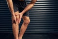 No pain, no gain. Studio shot of an unrecognizable holding his knee against a dark background.