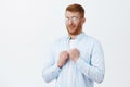 Studio shot of weak and silly mature redhead guy in transparent glasses and shirt, raising fists uncertainly, frowning