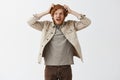 Studio shot of weird funny and panicking redhead guy with beard making faces scratching head insane shouting while