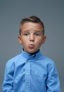 Playful boy making face and posing against grey background Royalty Free Stock Photo