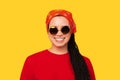 Studio shot of a wide smiling girl with box braids wearing sunglasses.