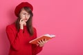 Studio shot of woman with concentrated facialexpression, holding textbook, studying to pass exam or reading interesting book, Royalty Free Stock Photo