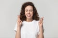 Studio shot woman with crossed fingers asks for good luck