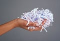 Protect your information. Studio shot of a womans hand holding a pile of shredded paper against a grey background.