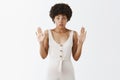 Studio shot of worried intense attractive African American with curly hairstyle raising palms in surrender gasping