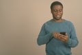 Young African man using mobile phone against gray background Royalty Free Stock Photo