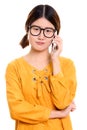 Studio shot of young angry Asian woman talking on mobile phone Royalty Free Stock Photo