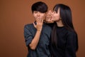 Young Asian lesbian couple together and in love against brown ba Royalty Free Stock Photo