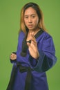 Young Asian woman wearing blue karate Gi against green background