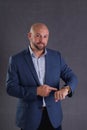 Studio shot of a young bald businessman in a suit checking time standing against gray background Royalty Free Stock Photo