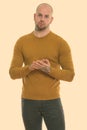 Studio shot of young bald muscular man standing with hands together Royalty Free Stock Photo