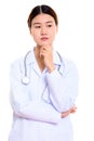 Studio shot of young beautiful Asian woman doctor thinking Royalty Free Stock Photo