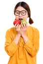 Studio shot of young beautiful Asian woman eating red apple and Royalty Free Stock Photo