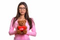 Studio shot of young beautiful Brazilian nerd woman holding tedd