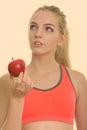 Face of young beautiful teenage girl holding red apple while thinking ready for gym Royalty Free Stock Photo