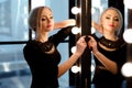 Studio shot of young and beautiful girl standing near mirror in black dress wearing in studio. Blonde girl Royalty Free Stock Photo