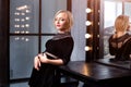 Studio shot of young and beautiful girl standing near mirror in black dress wearing in studio. Blonde girl Royalty Free Stock Photo