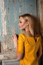 Studio shot of young and beautiful girl standing near old door in yellow leather dress wearing in studio. Blonde girl Royalty Free Stock Photo