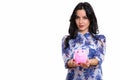 Studio shot of young beautiful Spanish businesswoman holding pig