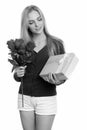 Studio shot of young beautiful teenage girl holding roses and looking at gift box ready for Valentine`s day Royalty Free Stock Photo