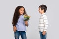 Studio shot of a boy giving flowers to a girl, isolated Royalty Free Stock Photo