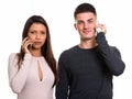 Studio shot of young couple talking on mobile phone together Royalty Free Stock Photo